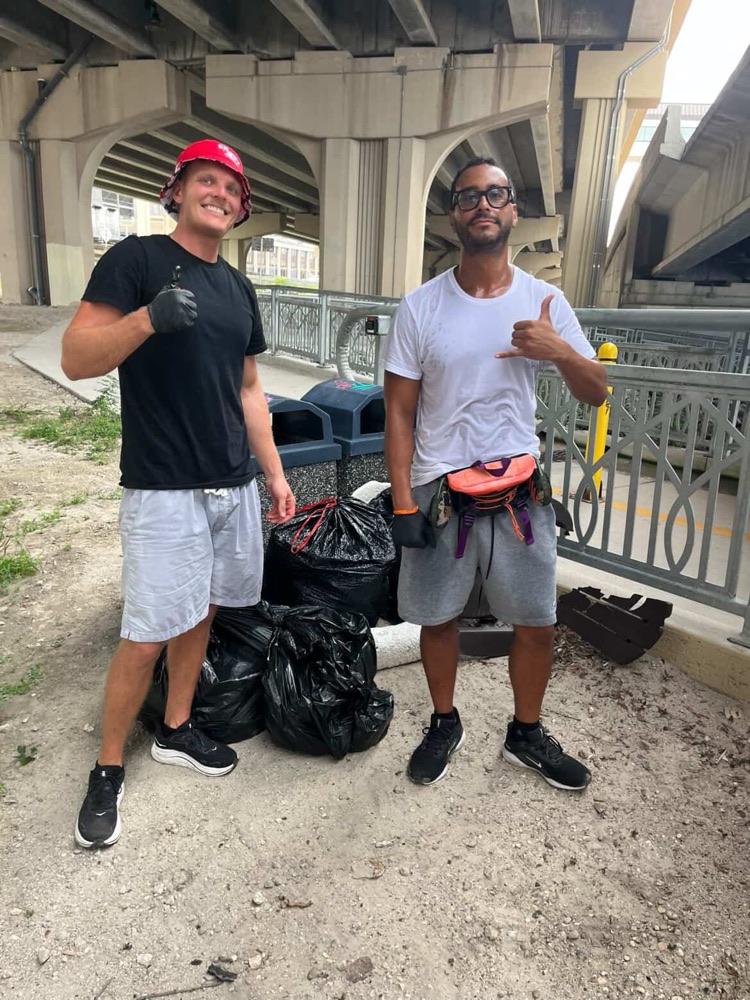 904 Walk Club volunteers with bags of collected trash under the Jacksonville bridge